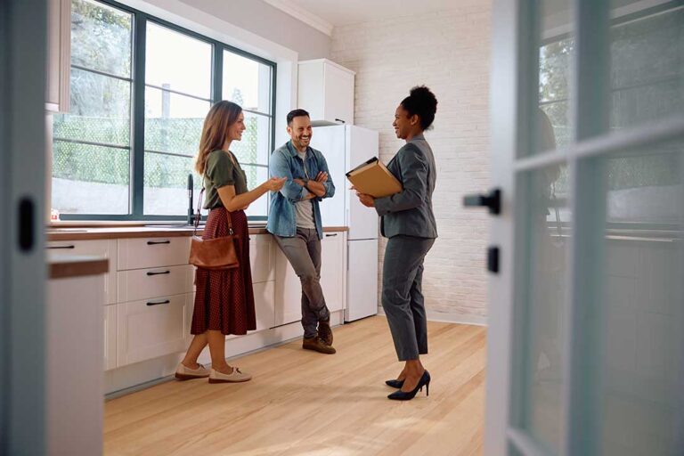 A family tours a bright, open living room with an agent, examining features and discussing home details.