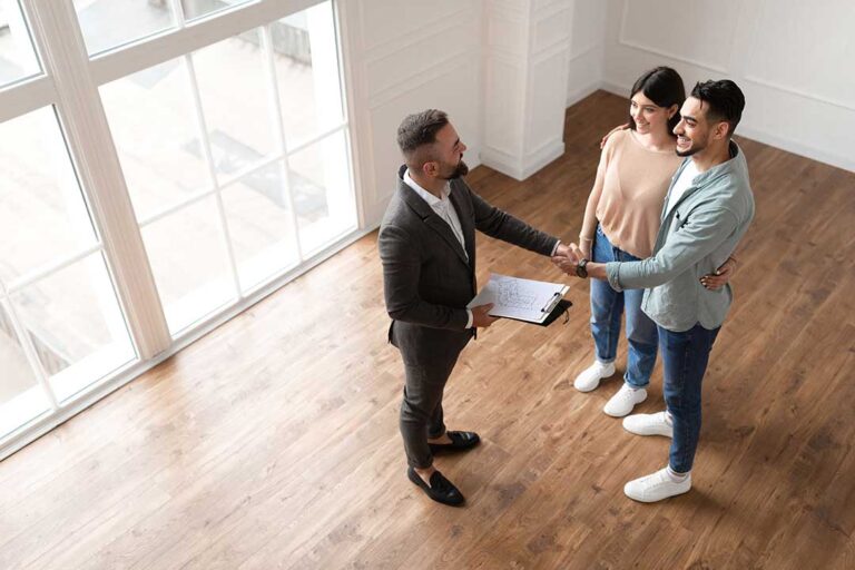 Homeowners reviewing property documents with a real estate agent at a dining table.